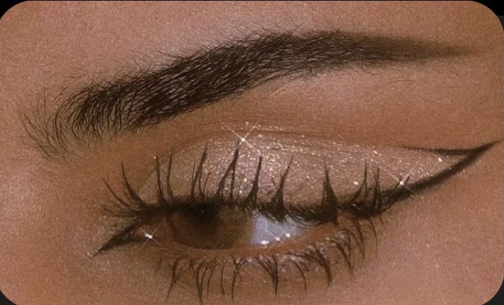 a woman's eye with long lashes and glitters on her eyeshade