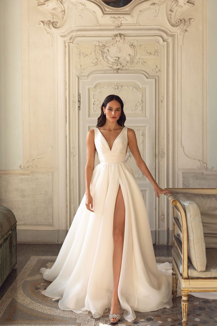 a woman in a white dress standing next to a chair