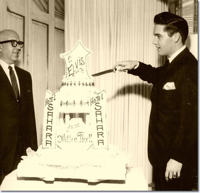 two men standing next to each other in front of a white cake with writing on it