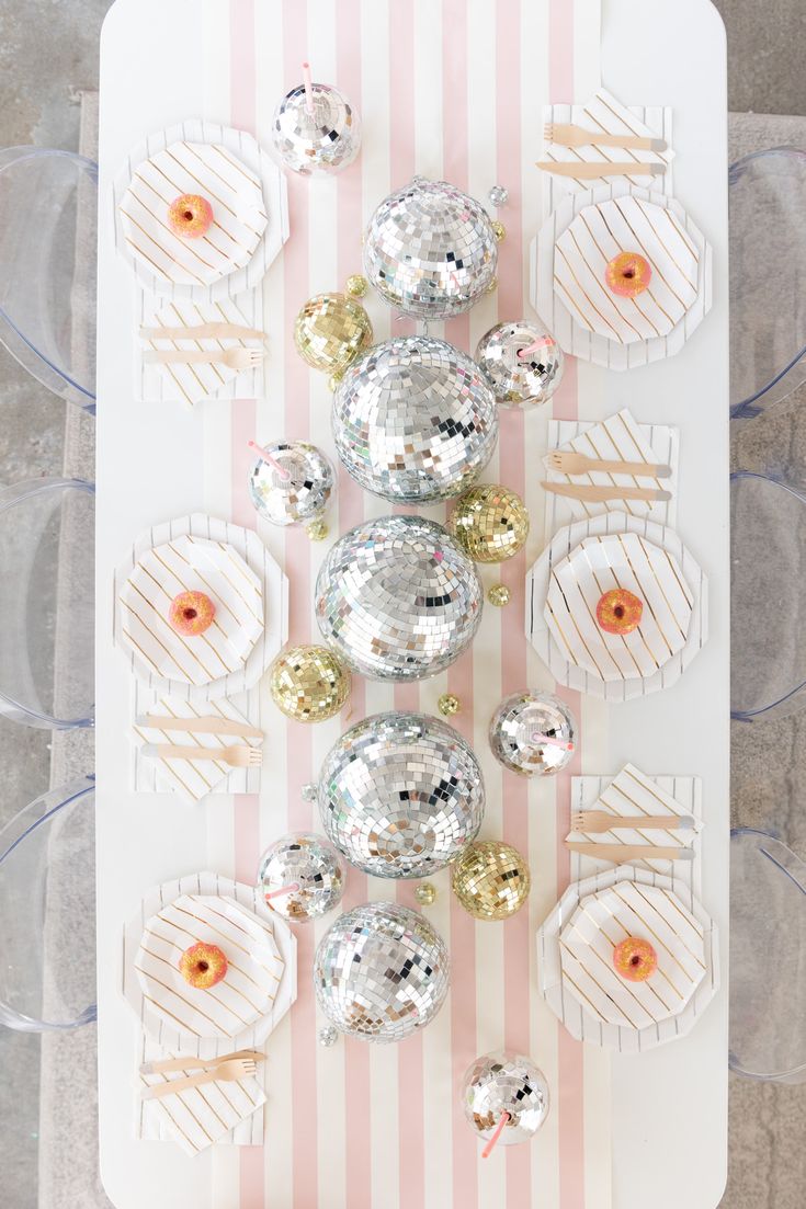 a table topped with lots of shiny silver and gold ornaments on top of a white board