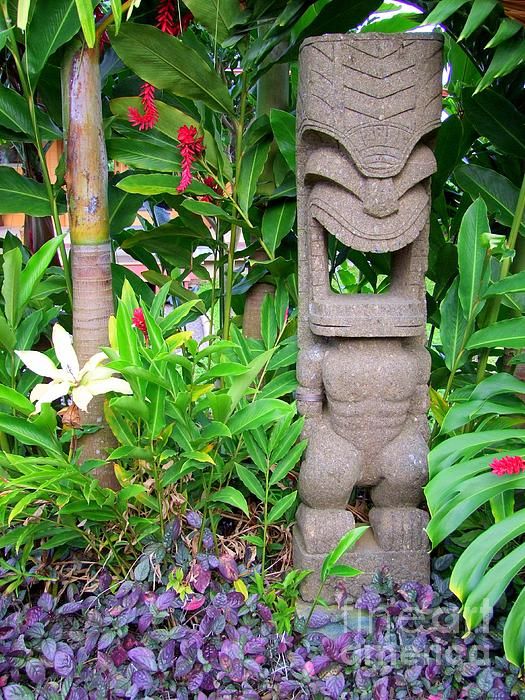 a statue in the middle of some plants and flowers