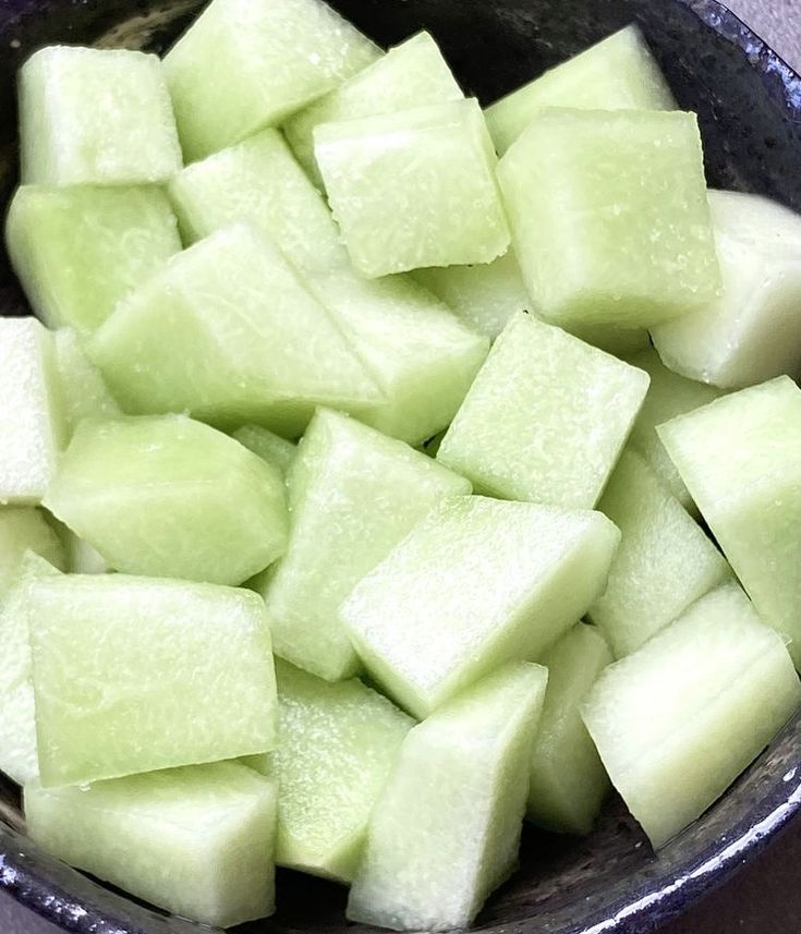 a bowl filled with cut up cucumbers on top of a gray countertop