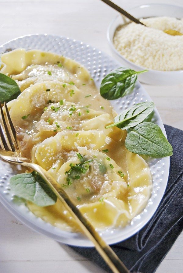 a white plate topped with ravioli and spinach