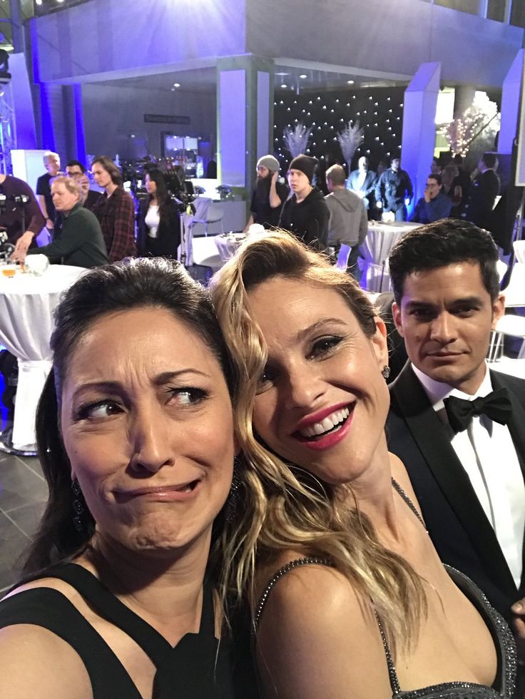 two women pose for a photo in front of an audience at a formal dinner event