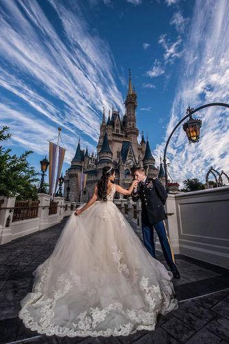 a bride and groom pose in front of the castle at disney's magic kingdom