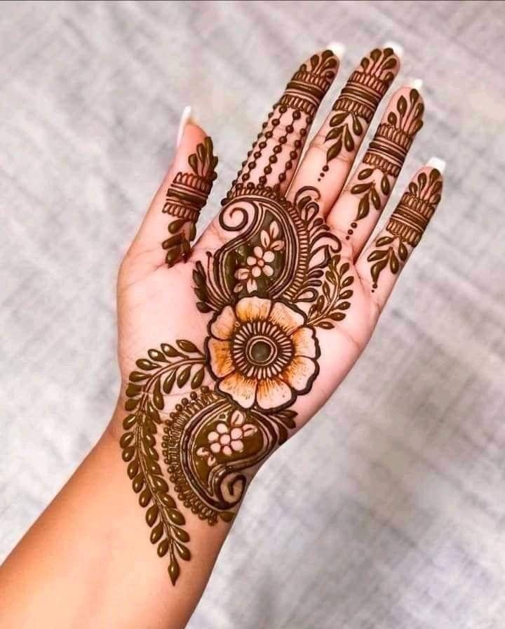 a woman's hand with henna tattoos and flowers on her hands, showing the intricate