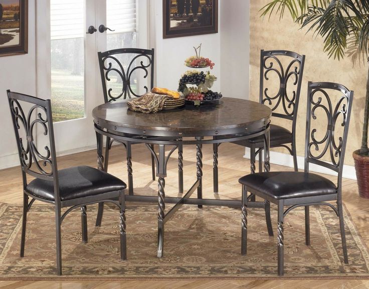 a dining room table with four chairs and a rug on the floor in front of it