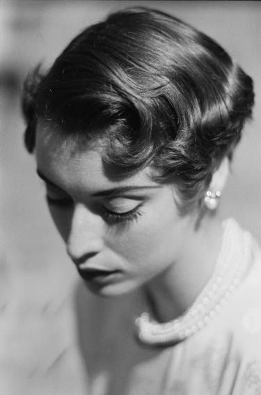 an old black and white photo of a woman with her eyes closed wearing pearl earrings