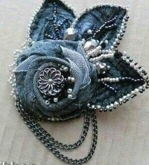 a blue flower brooch with pearls on it's end and chain attached to it