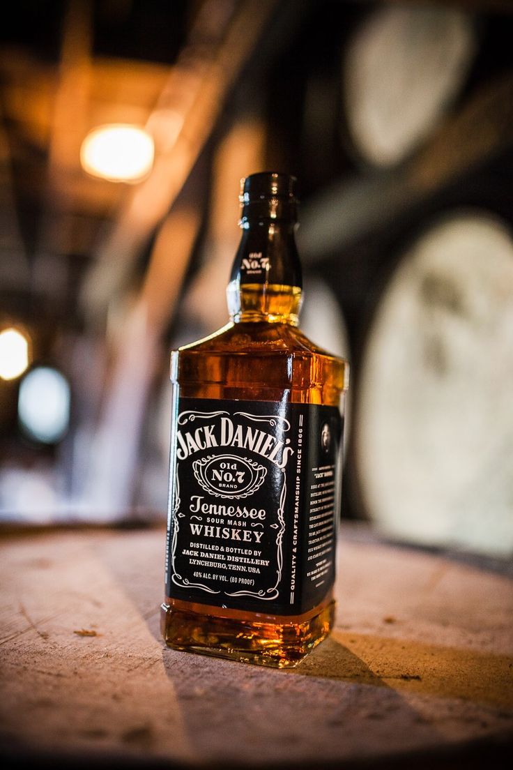 a bottle of jack daniels whiskey sitting on top of a barrel