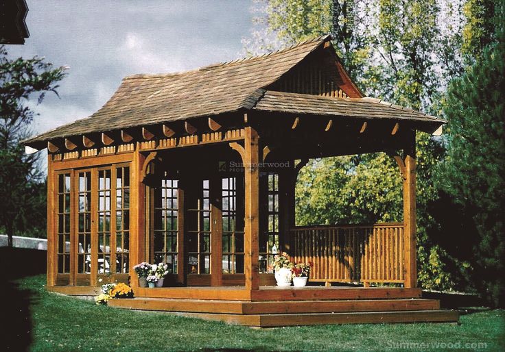 a wooden gazebo sitting on top of a lush green field