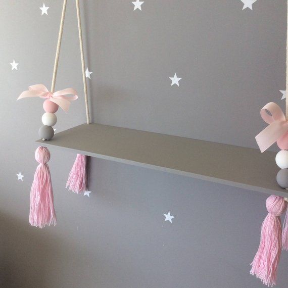 a gray shelf with pink tassels hanging from it's sides and stars on the wall