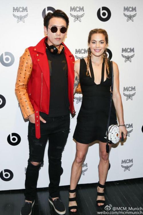 two people standing next to each other in front of a white wall and black floor