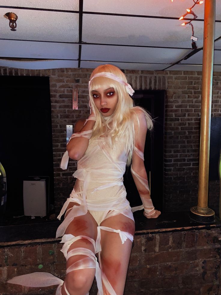 a woman dressed in white posing for the camera with her legs wrapped around and stockings on