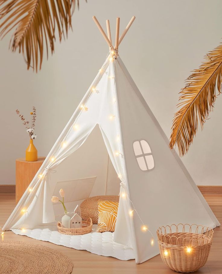 a white teepee with lights on it and a basket in front of the teepee