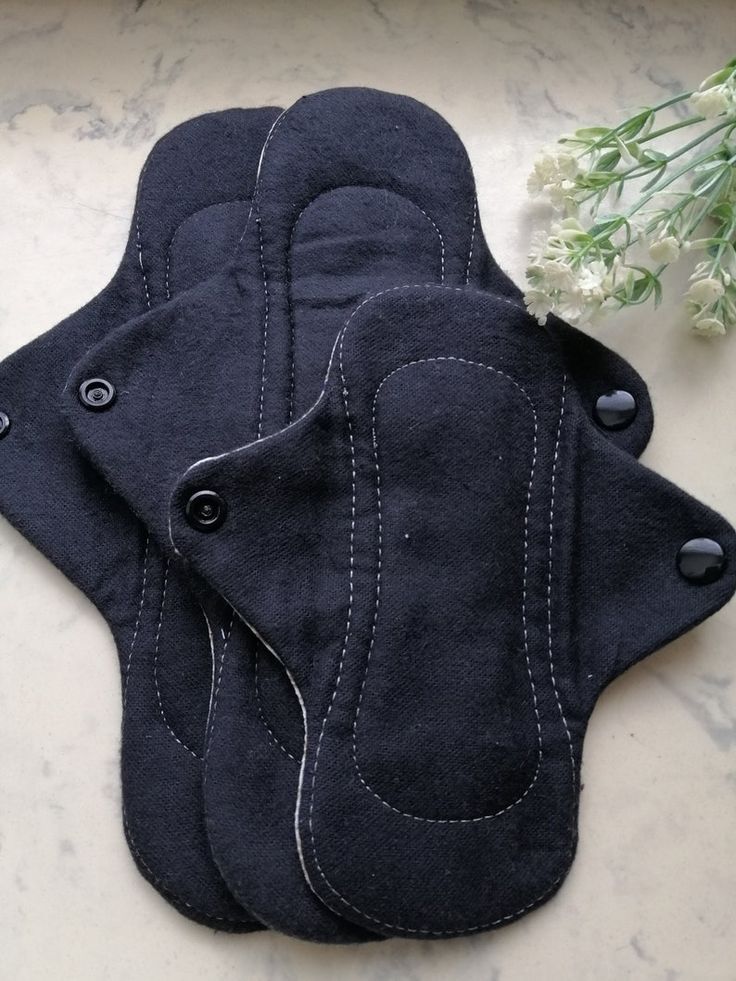 three black oven mitts sitting on top of a counter next to a white flower