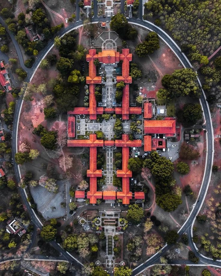 an aerial view of a large orange building in the middle of a road with trees around it