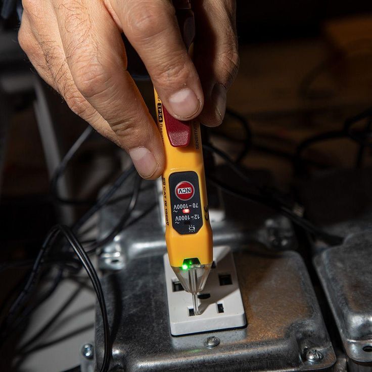 a person using a yellow and black tool to check the voltages on an electrical device