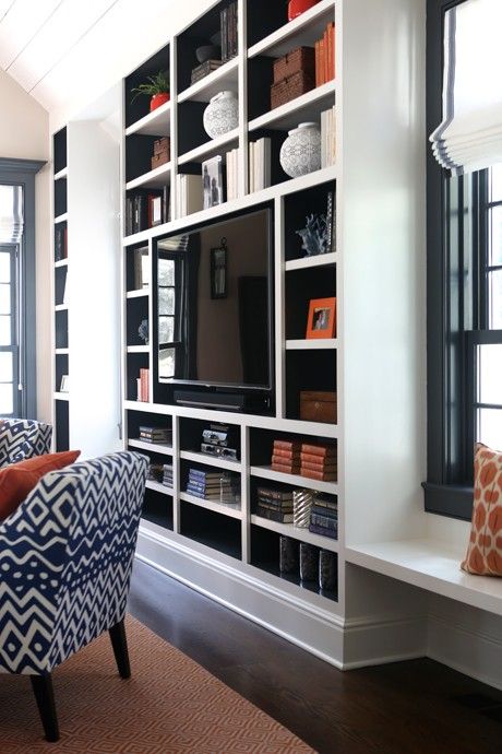 a living room filled with furniture and a flat screen tv on top of a book shelf