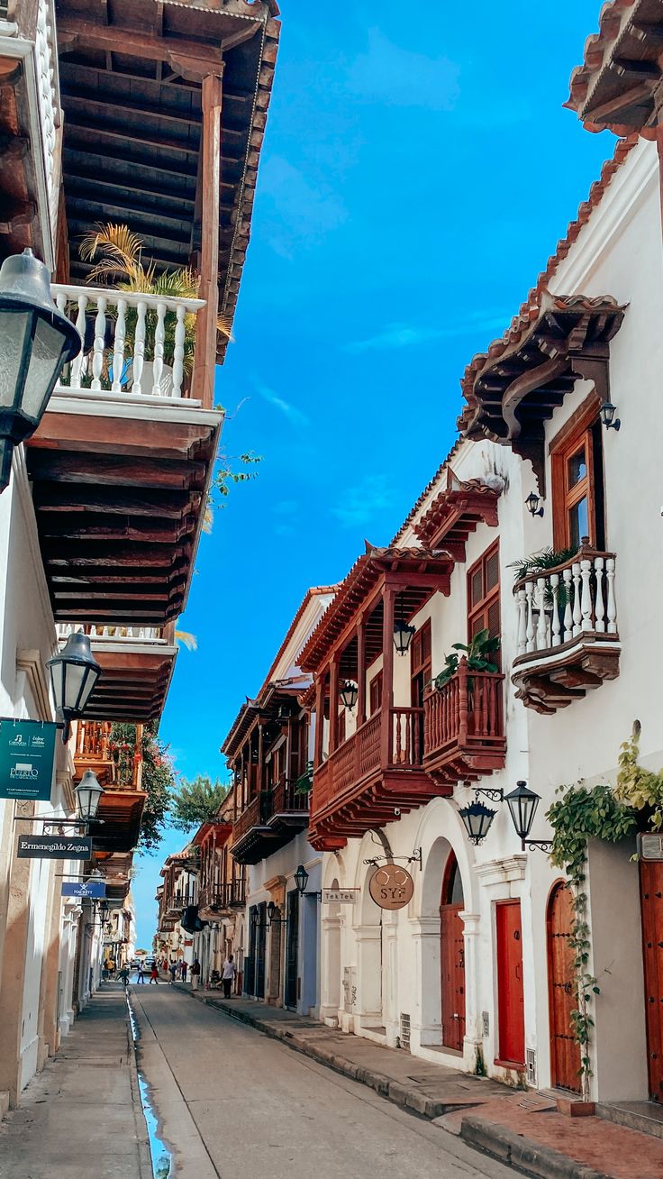 an empty street lined with white buildings and wooden balconies