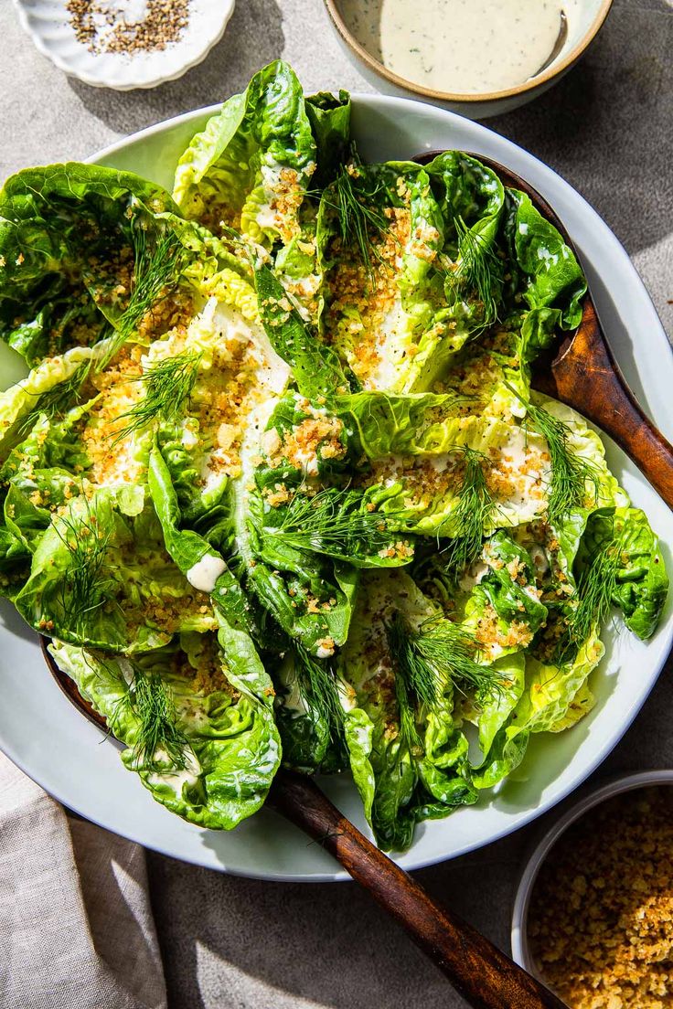 a white plate topped with lettuce covered in cheese and seasoning next to other dishes