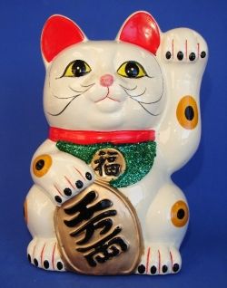 a white cat figurine sitting on top of a blue background with chinese writing