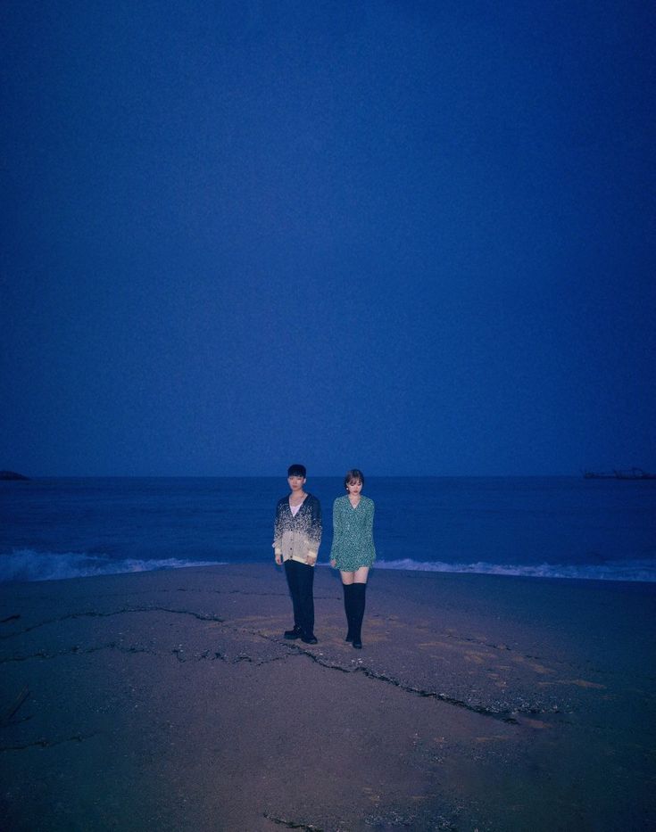 two people standing on the beach at night