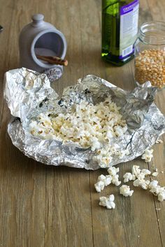 some food is sitting on a table with tin foil and other items around it, including popcorn