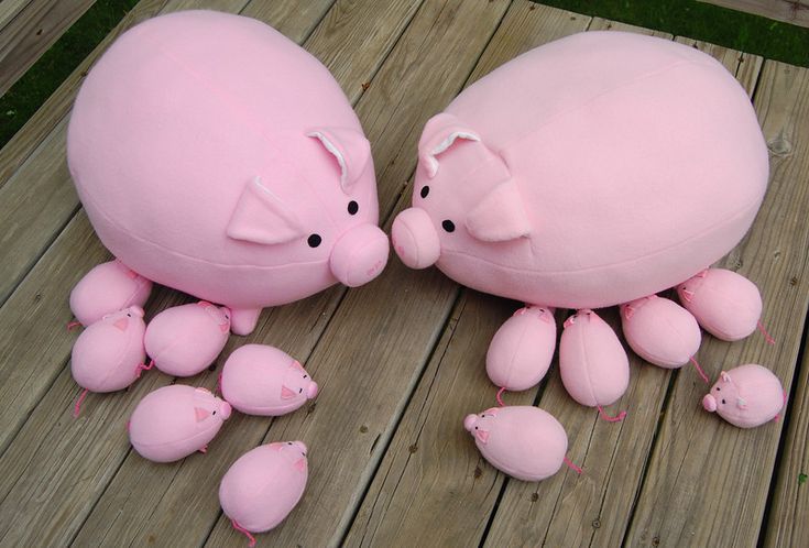 two pink stuffed animals sitting next to each other on a wooden floor with smaller ones around them