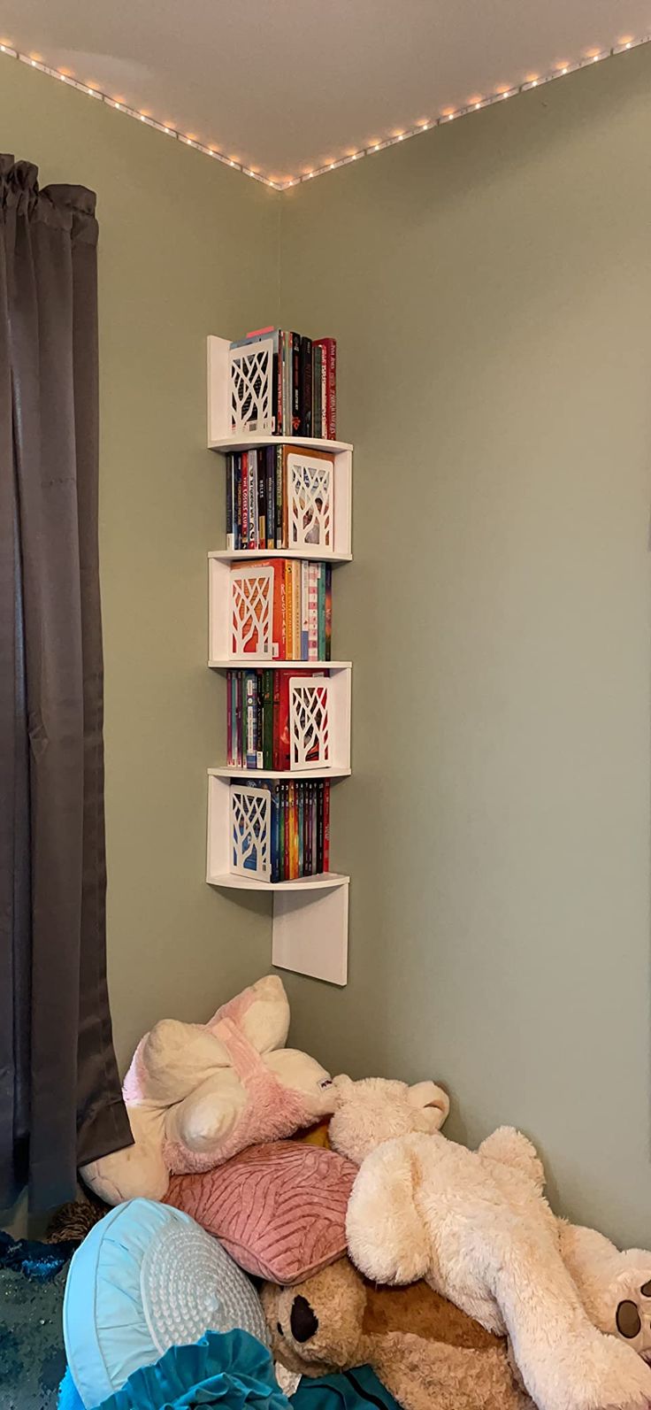 a room with stuffed animals on the floor and bookshelf in the corner behind it