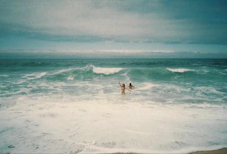 two people are standing in the ocean waves