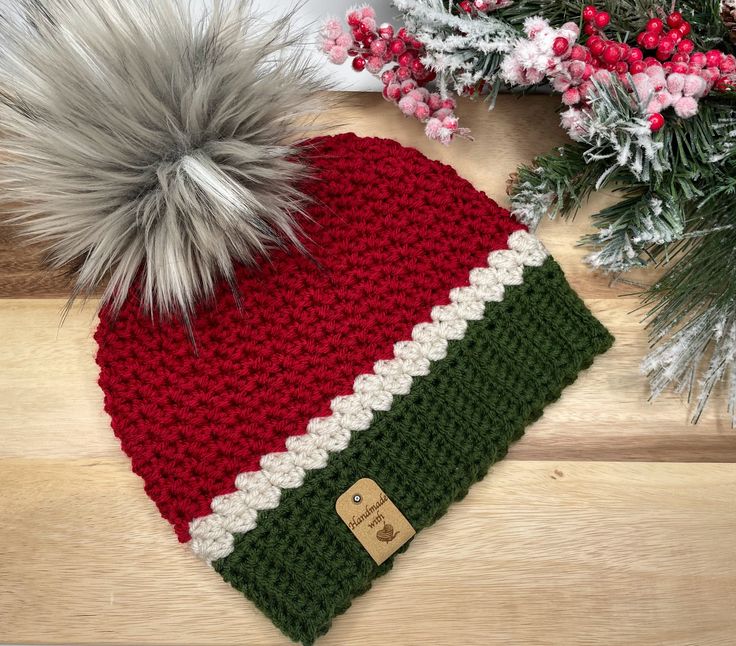 a red, white and green knitted hat with pom - pom