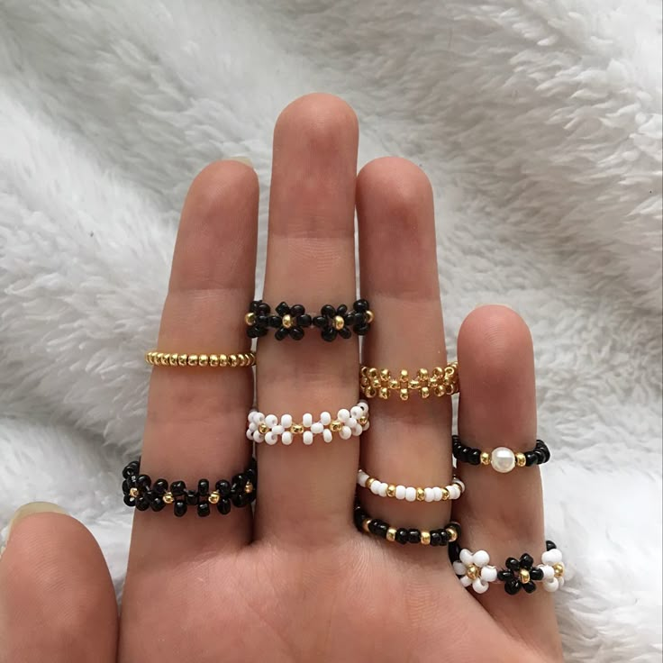 a hand holding five different types of beaded bracelets on it's fingers