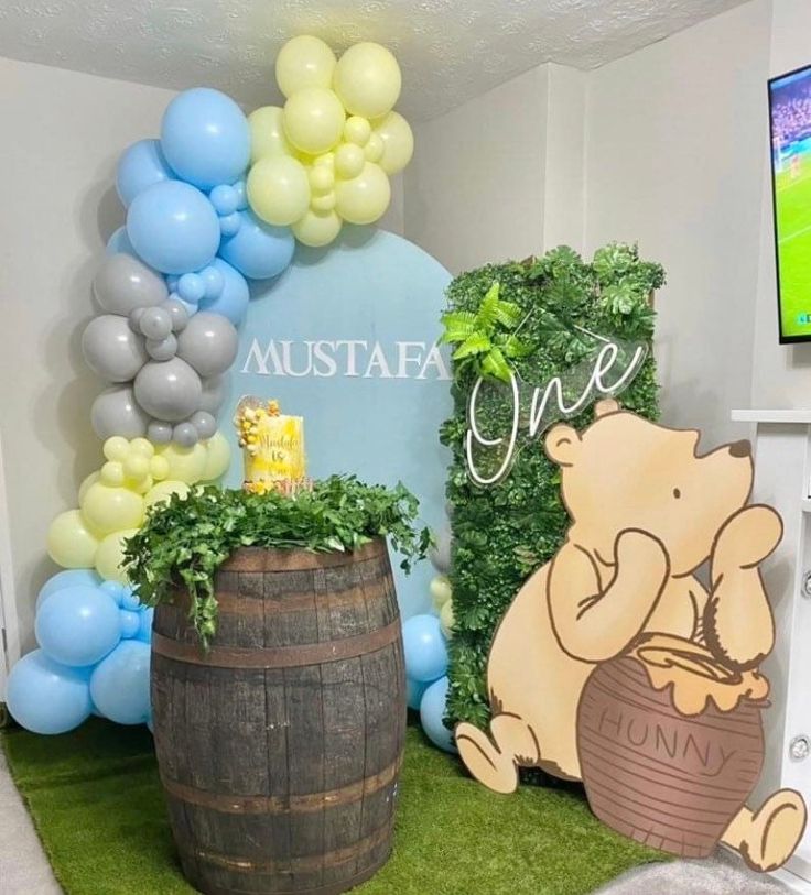 a winnie the pooh themed birthday party with balloons and decorations on display in front of a tv