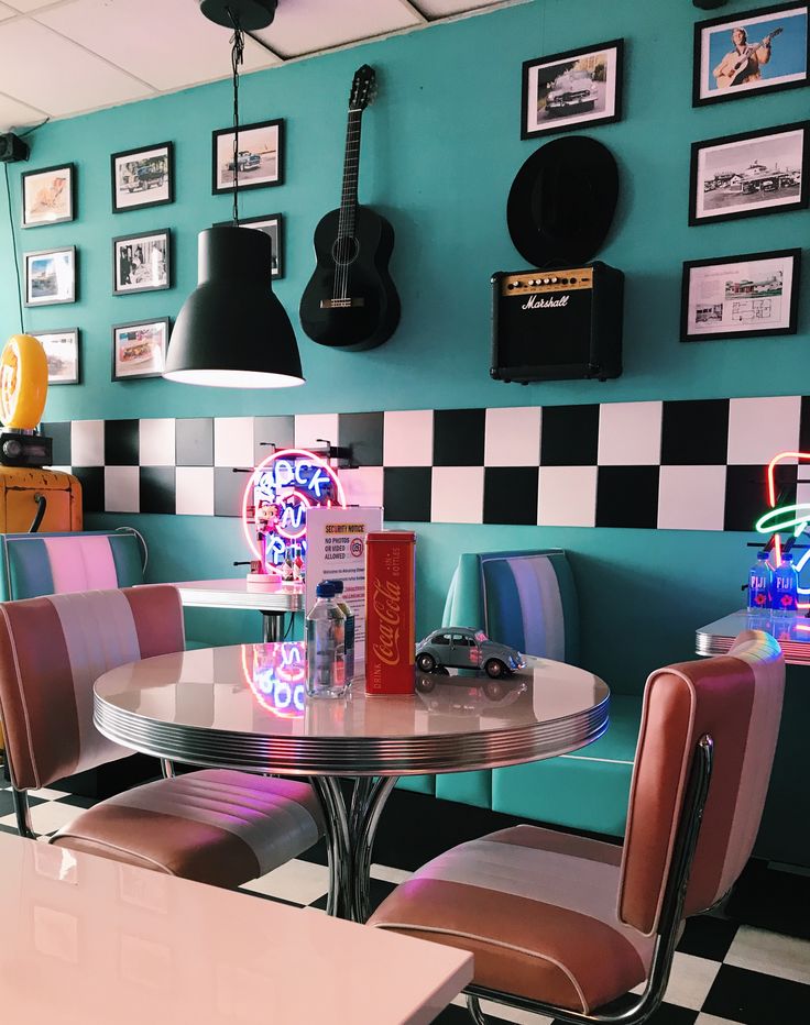 a table with four chairs and a guitar on the wall in a room that has checkered walls