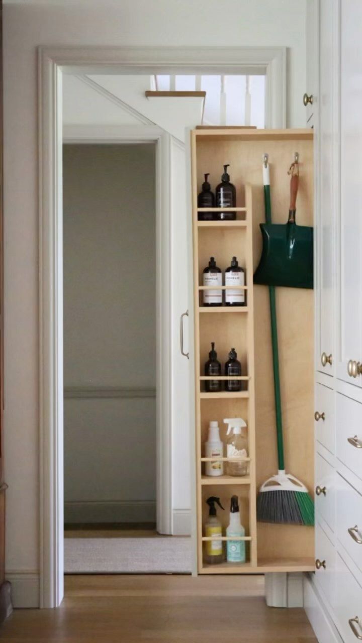 an open cabinet in the hallway is filled with cleaning products