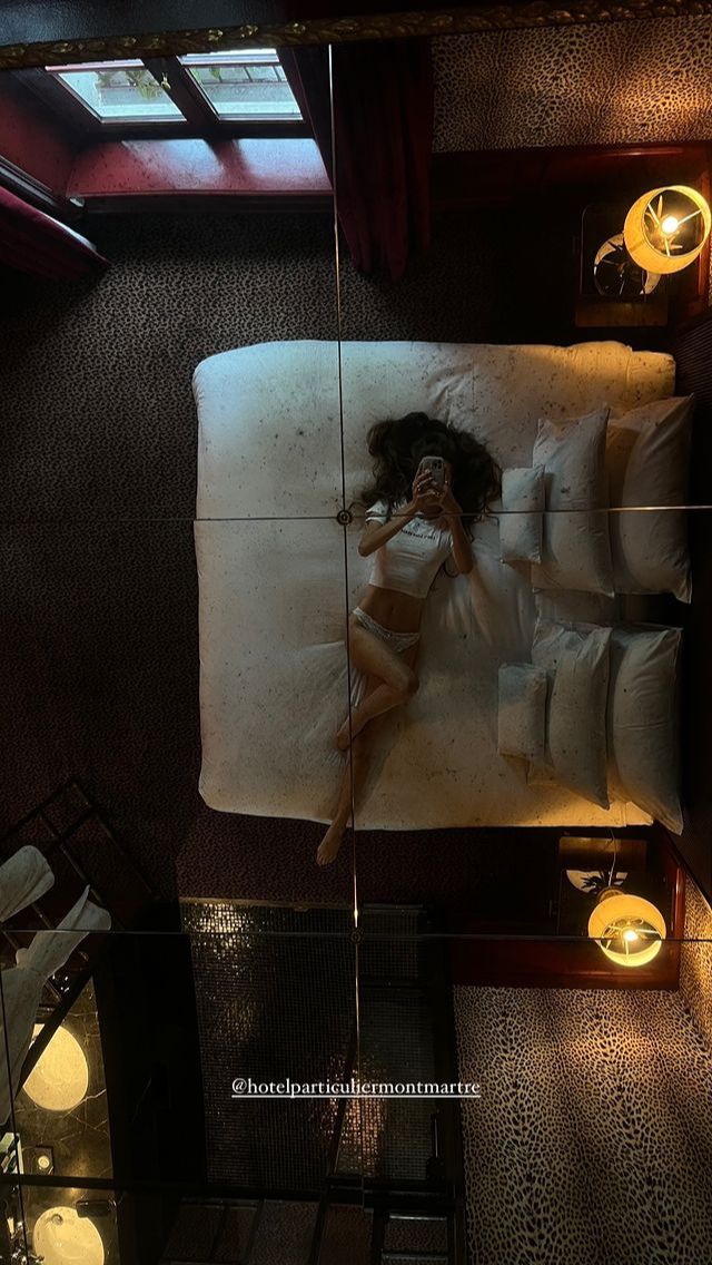 a woman laying on a bed in a room with lights around her and an overhead view of the floor