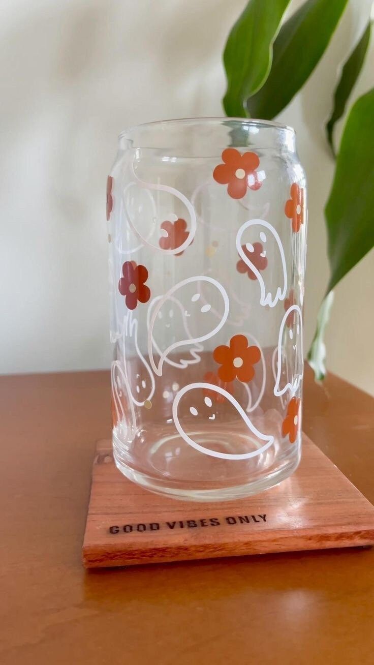 a glass vase sitting on top of a wooden table next to a potted plant