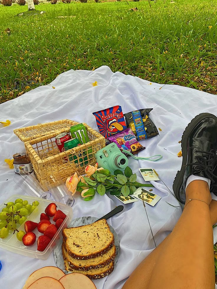 a person is sitting on a blanket with food and fruit in front of them,