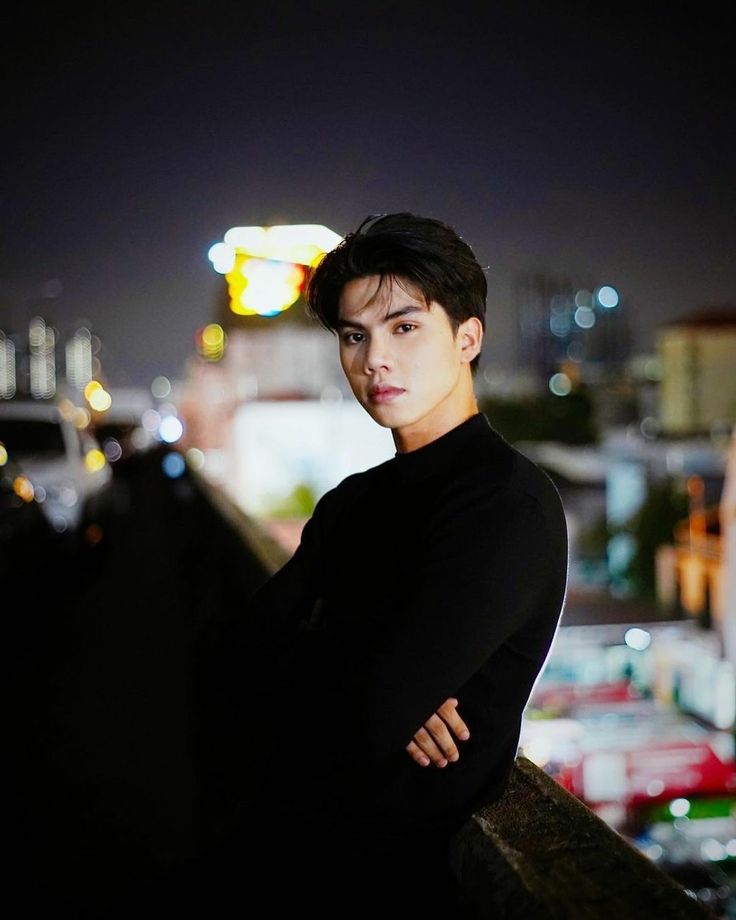 a young man standing on top of a bridge at night