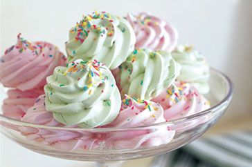 three cupcakes with white frosting and sprinkles in a glass dish