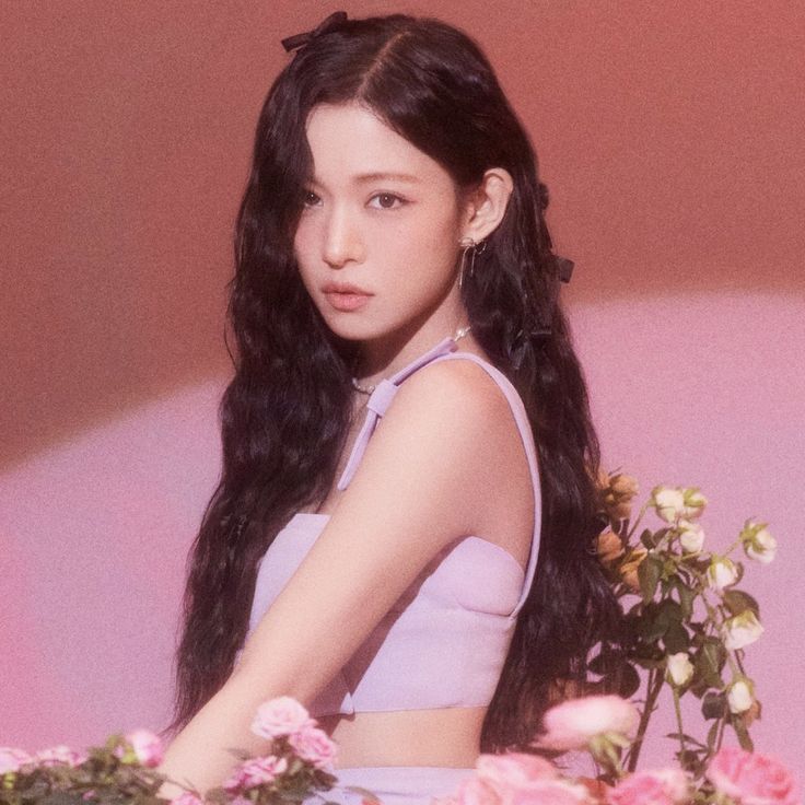 a woman with long black hair sitting in front of flowers