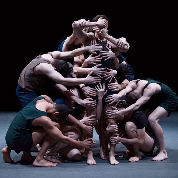 a group of men standing around each other on top of one another in front of a black background