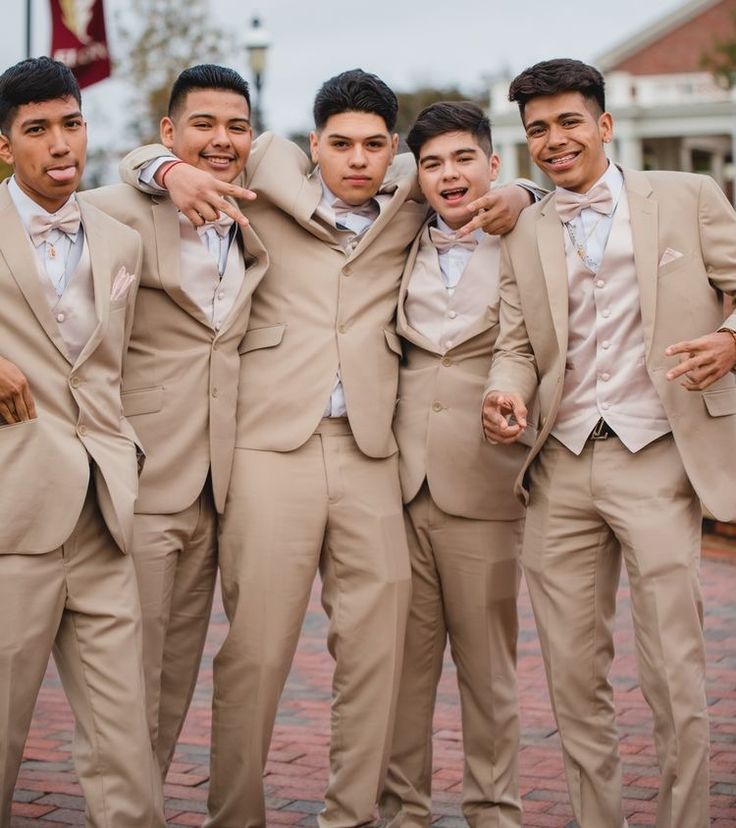 a group of young men standing next to each other wearing tan suits and bow ties