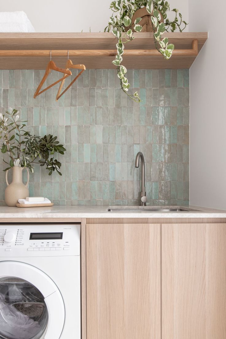 a washer and dryer sitting in a kitchen next to a counter with plants on it