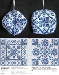 two pieces of blue and white cross - stitch fabric hanging from hooks, each with different designs on them