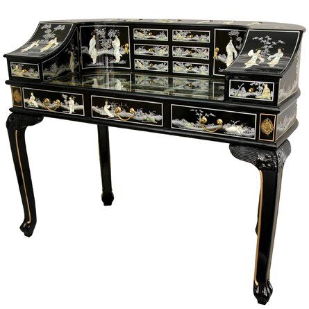 an antique desk with black and gold decorations on it's drawers, including a glass top