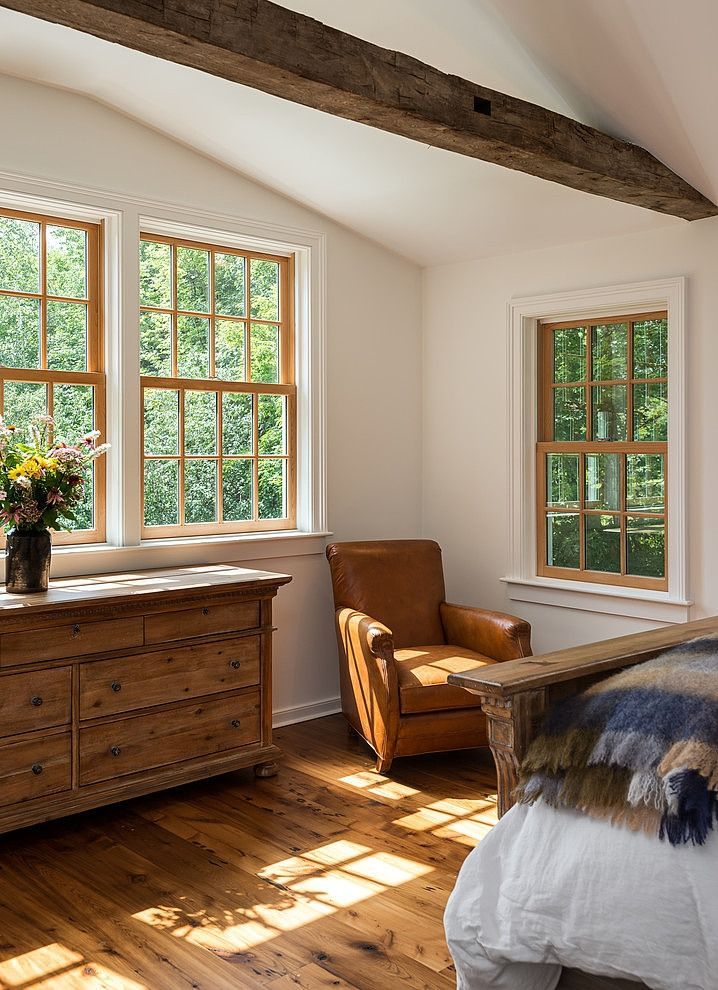 a bedroom with wooden floors and windows in the ceiling, along with a bed that has white sheets on it