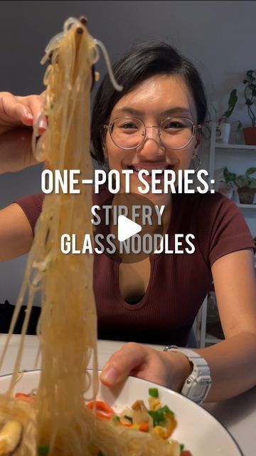 a woman sitting in front of a plate of food with chopsticks sticking out of it