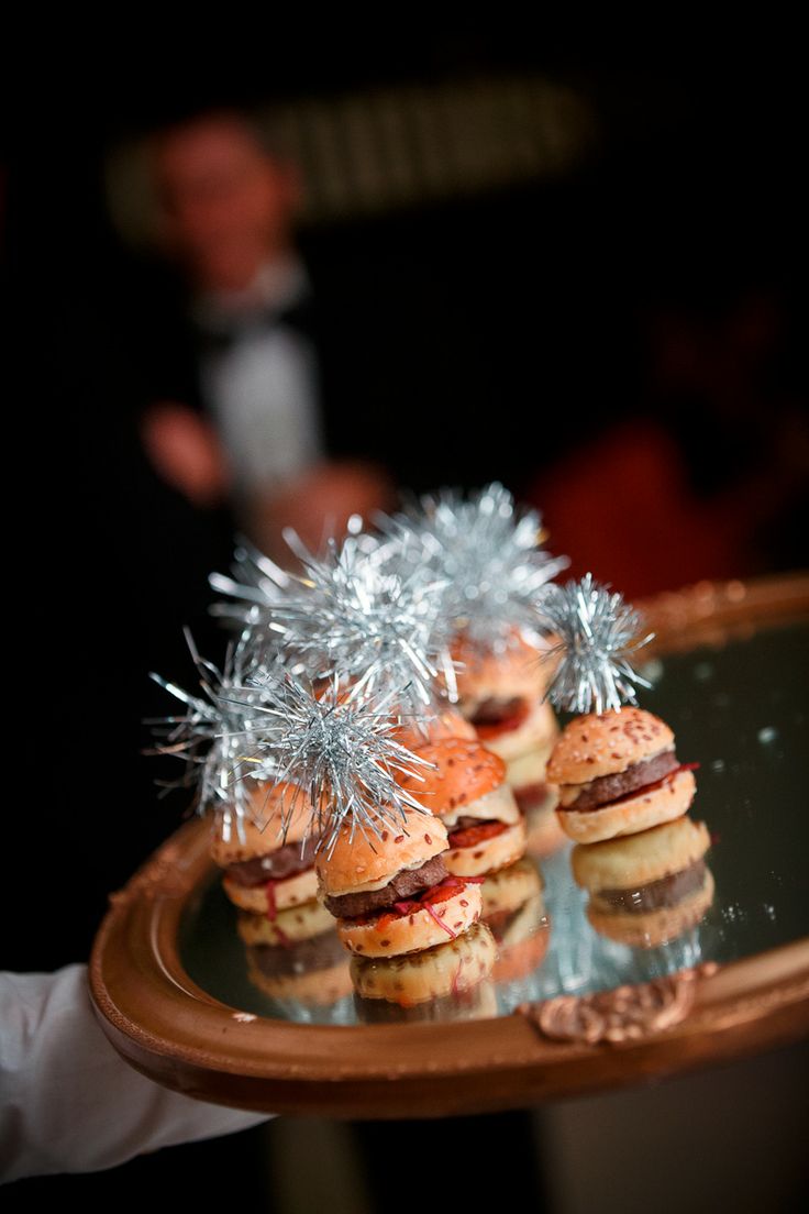 small sandwiches with tinsel wrapped around them on a tray in front of a man